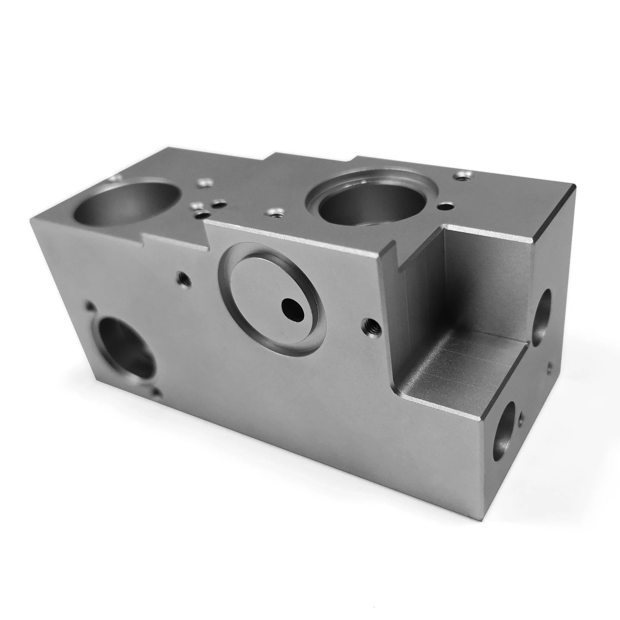 A machined aluminum manifold block with bored pockets and side ports