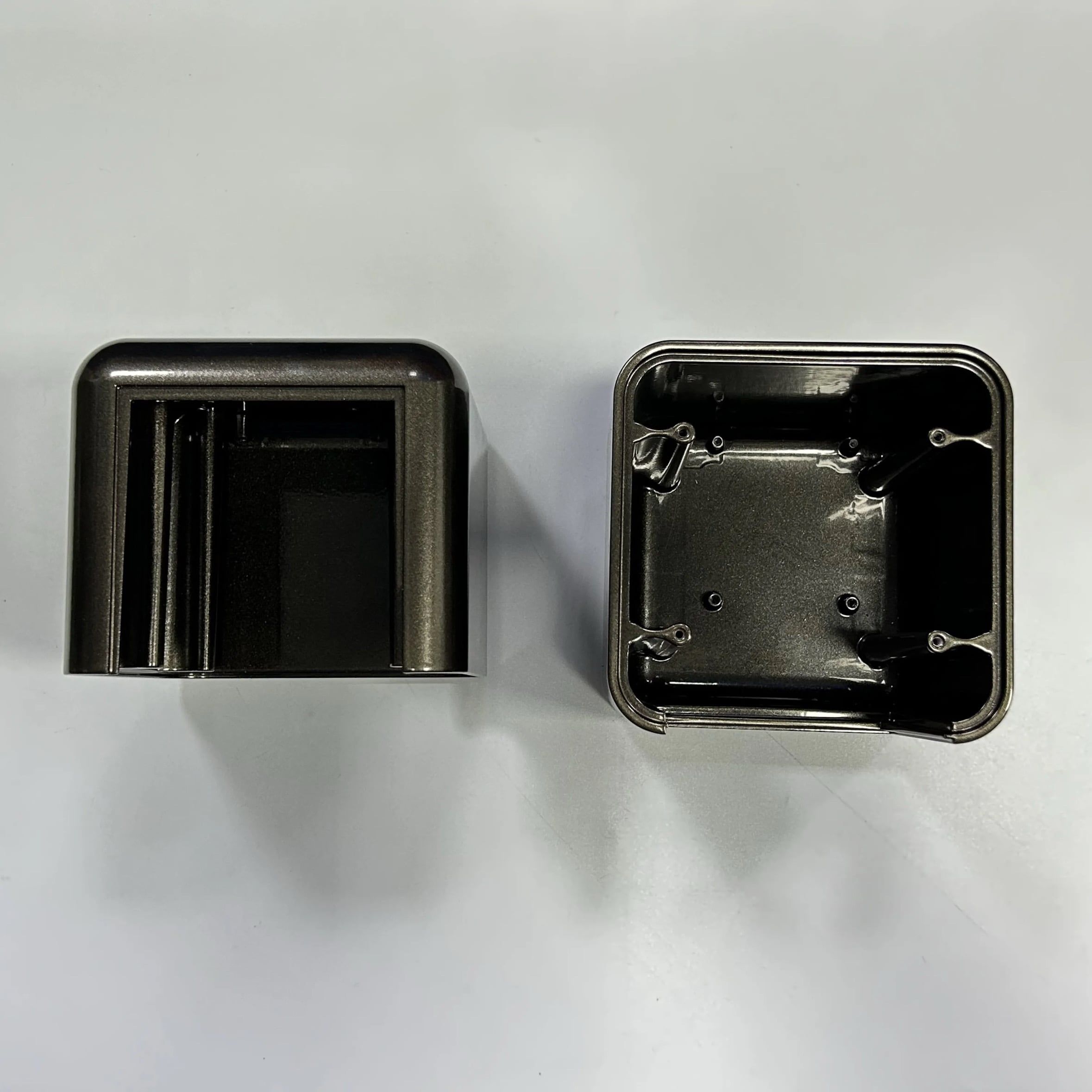 A dark anodized aluminum enclosure cap and open housing showing internal bosses