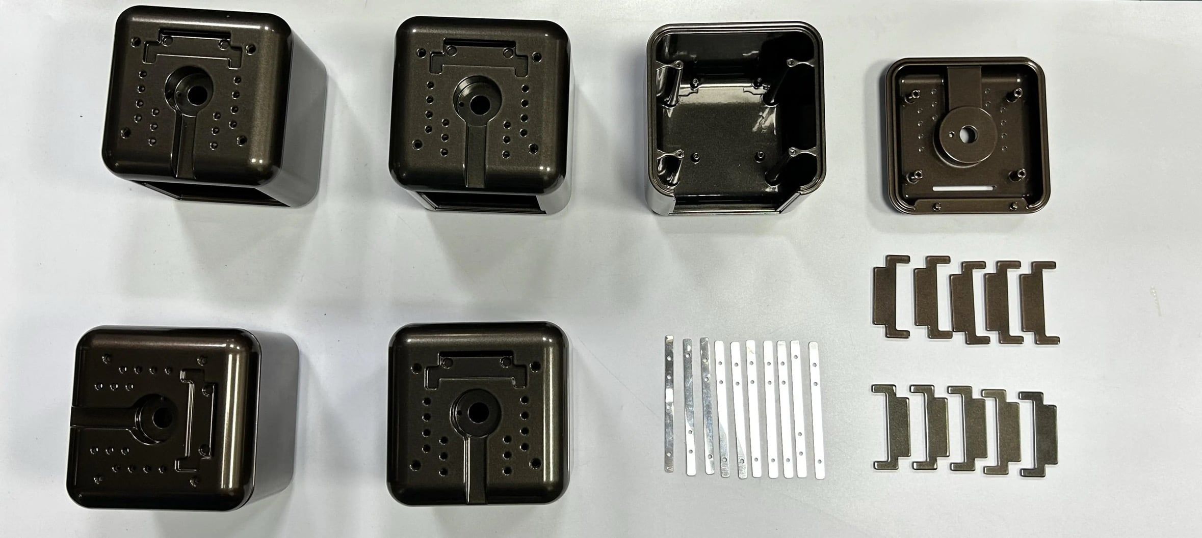 A set of dark anodized aluminum enclosures with machined hole patterns and clips