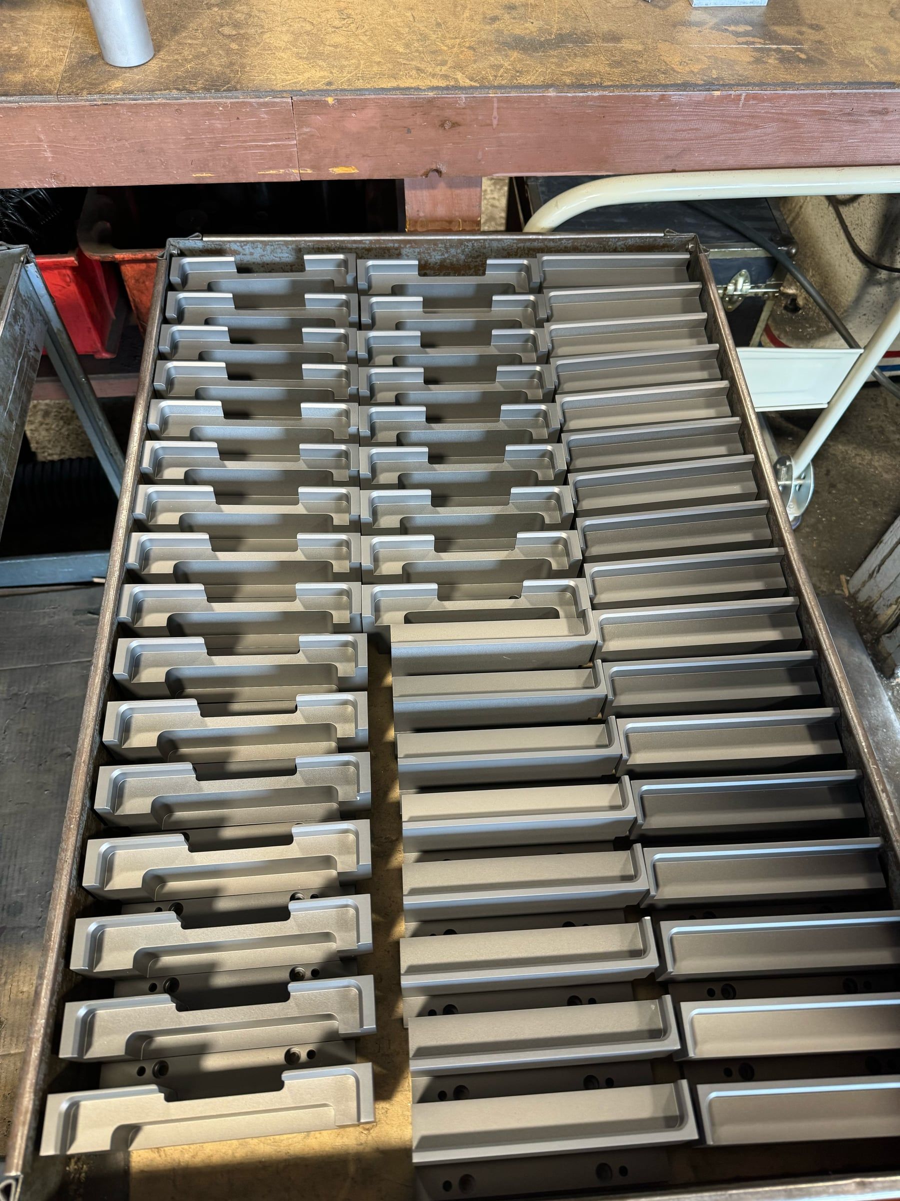 A tray of identical machined brackets in a bronze finish